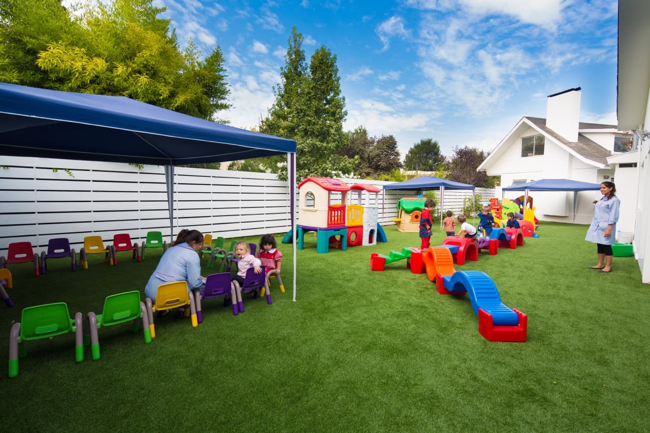 Niños y educadora en patio exterior del Jardín Infantil Marco Polo, Las Condes